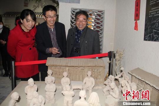 图为赵铁军向参观者介绍自己创作的泥塑作品。　郭惠民　摄