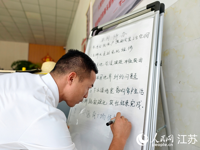 戴虎在便民服务站的“民情小黑板”上记录待办事项。人民网记者 马晓波摄