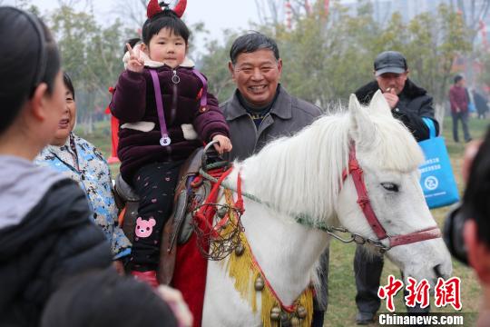 小朋友尝试坐白马很开心。　泱波　摄