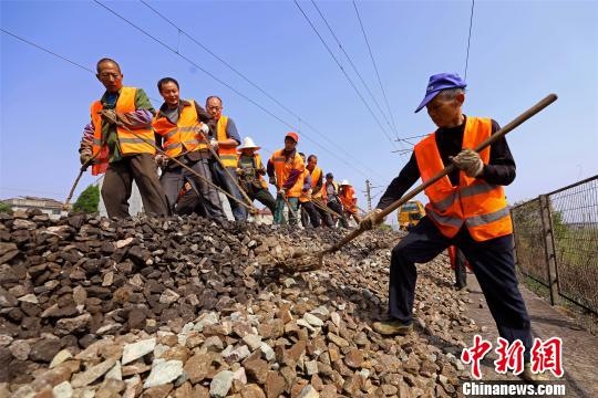 工人们在铁路线上对清筛作业后的线路进行石碴回填作业。　汪翰 摄